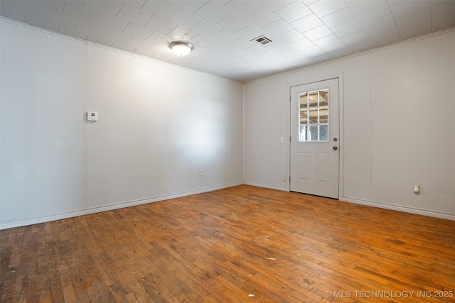 unfurnished room with visible vents, baseboards, hardwood / wood-style flooring, and crown molding