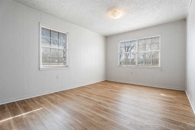 spare room featuring light wood-style floors and a textured ceiling