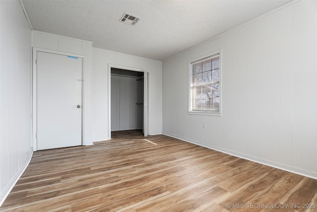 unfurnished bedroom with light wood-style flooring, a closet, visible vents, and a textured ceiling