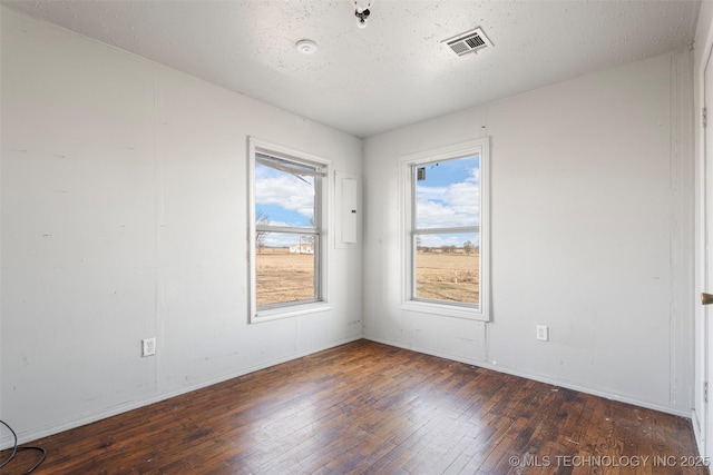 empty room with baseboards, wood-type flooring, visible vents, and a textured ceiling