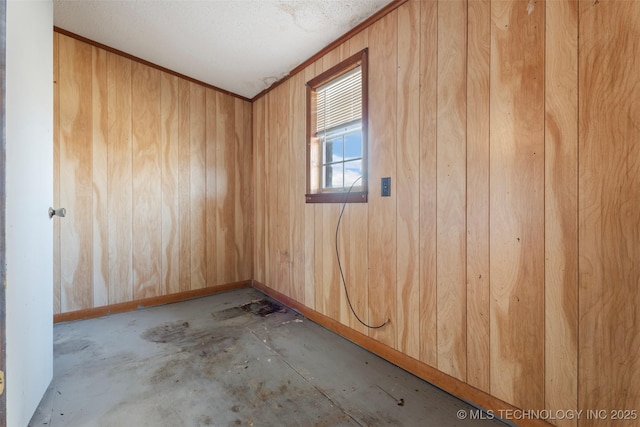 unfurnished room featuring baseboards, wood walls, and crown molding