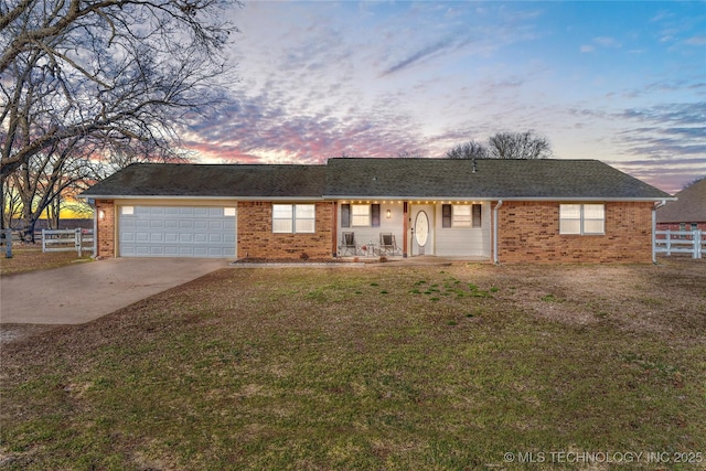 ranch-style house featuring an attached garage, brick siding, fence, driveway, and a front lawn