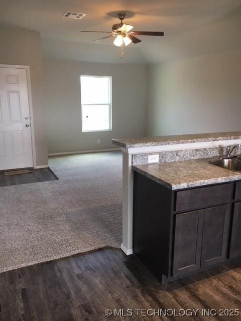 kitchen with baseboards, visible vents, a ceiling fan, dark wood-type flooring, and a sink