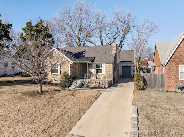 single story home featuring a garage, fence, stone siding, driveway, and a front lawn