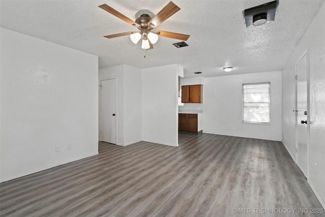 unfurnished living room with a ceiling fan, visible vents, a textured ceiling, and wood finished floors