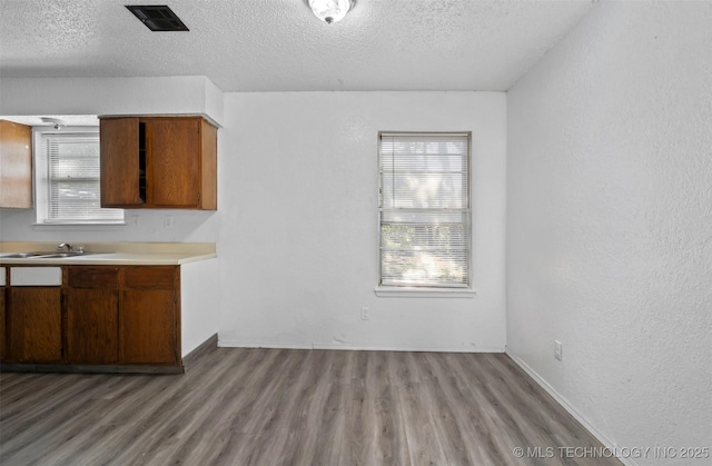 kitchen with visible vents, brown cabinets, wood finished floors, light countertops, and a textured ceiling