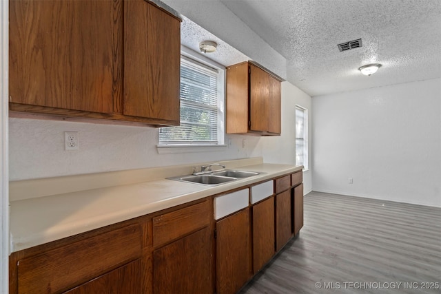 kitchen with light countertops, visible vents, light wood-style floors, a sink, and a textured ceiling