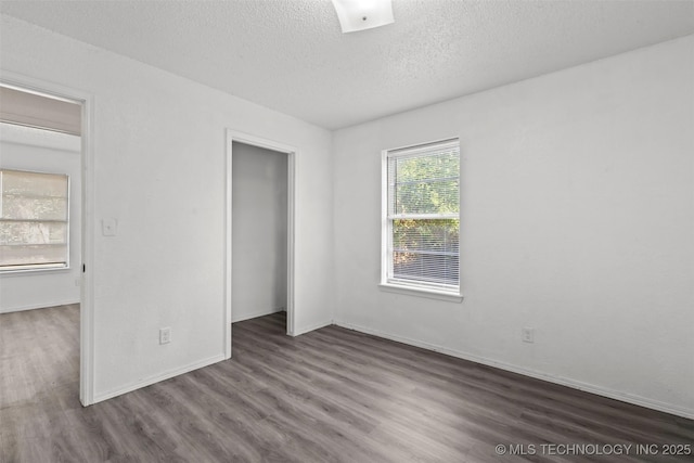 unfurnished bedroom with a closet, a textured ceiling, baseboards, and wood finished floors