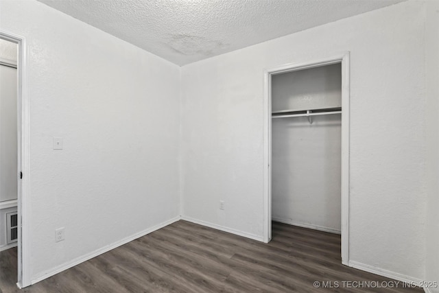 unfurnished bedroom with a closet, baseboards, dark wood finished floors, and a textured ceiling