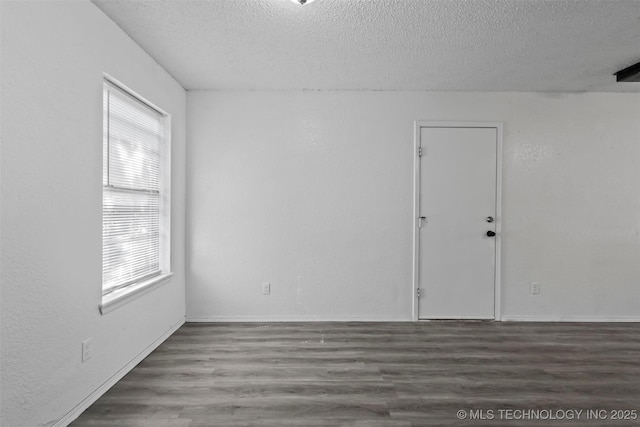 spare room with a textured ceiling, baseboards, and wood finished floors