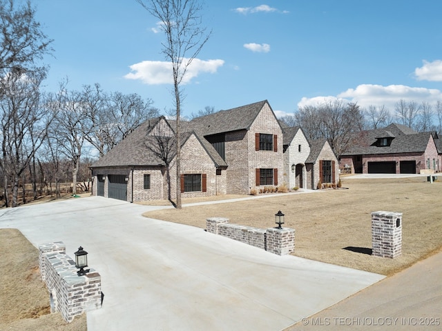 french country style house with concrete driveway, brick siding, roof with shingles, and an attached garage