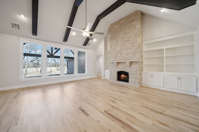 unfurnished living room with a fireplace, visible vents, a ceiling fan, wood finished floors, and beamed ceiling