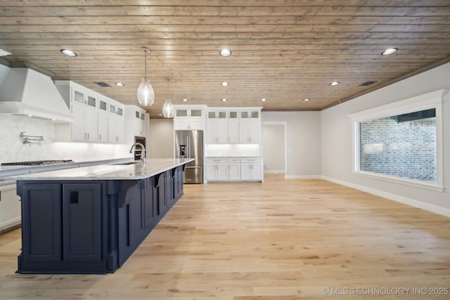 kitchen featuring white cabinets, stainless steel appliances, light wood-style floors, premium range hood, and a sink