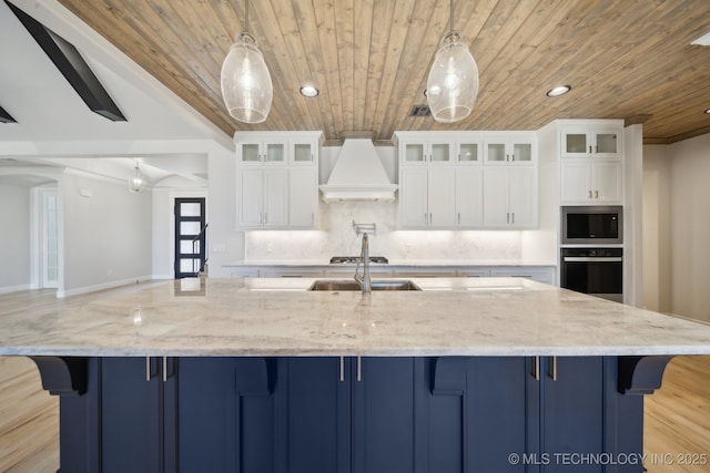 kitchen featuring blue cabinetry, premium range hood, stainless steel microwave, and wall oven