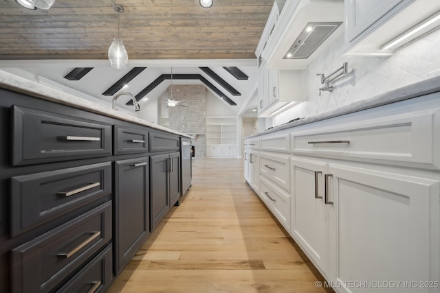 kitchen featuring vaulted ceiling with beams, light wood-style flooring, white cabinets, tasteful backsplash, and decorative light fixtures