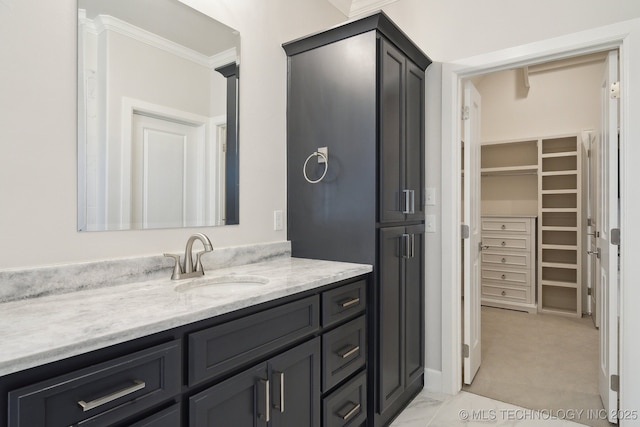 bathroom featuring a walk in closet, crown molding, and vanity