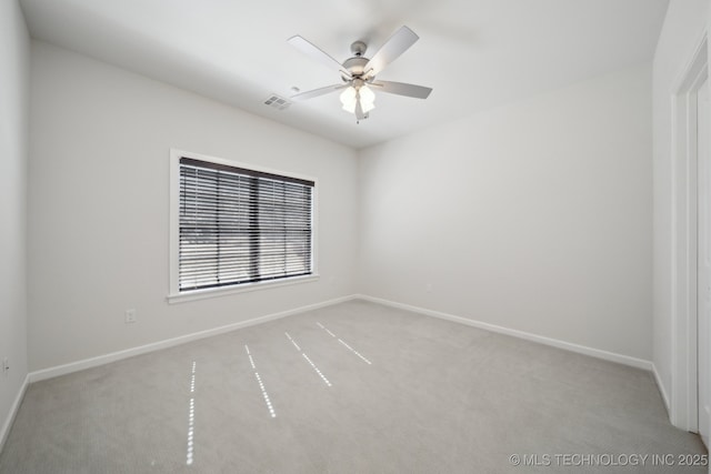 carpeted spare room featuring baseboards, visible vents, and a ceiling fan