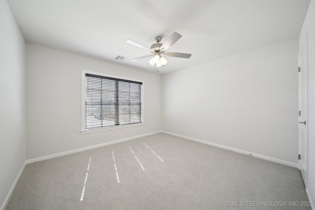 spare room with carpet floors, visible vents, ceiling fan, and baseboards