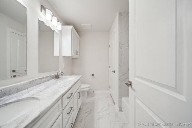 bathroom with marble finish floor, double vanity, a sink, and toilet