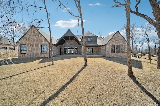 rear view of property featuring brick siding and fence