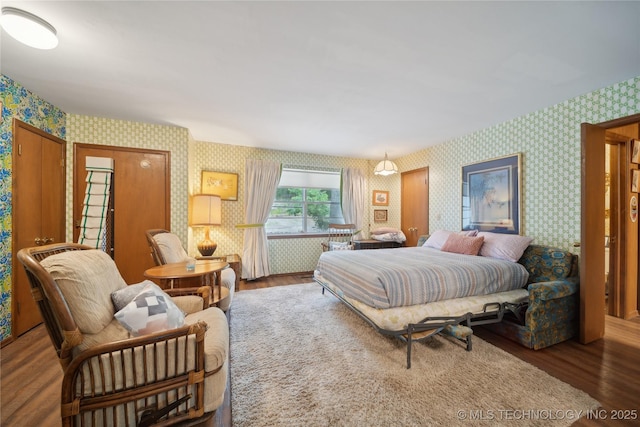 bedroom with wallpapered walls and wood finished floors