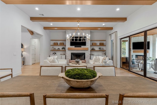 living room featuring a large fireplace, beamed ceiling, recessed lighting, and a notable chandelier