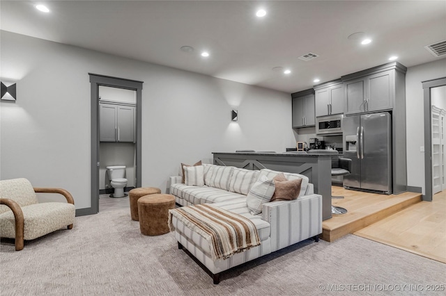 living room with light wood-style floors, baseboards, visible vents, and recessed lighting