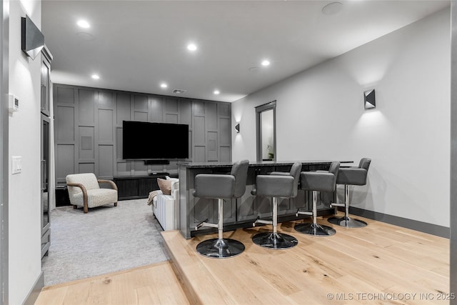 home theater room with a dry bar, visible vents, baseboards, wood finished floors, and recessed lighting