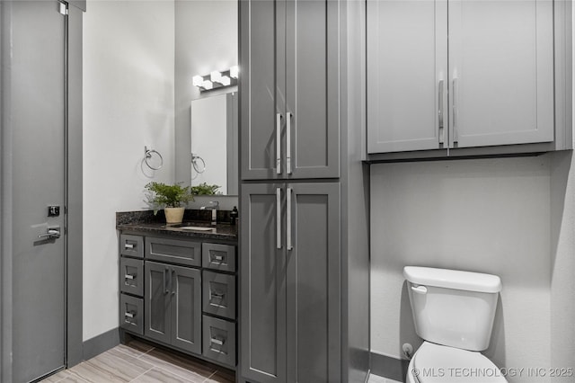 bathroom featuring toilet, baseboards, and vanity