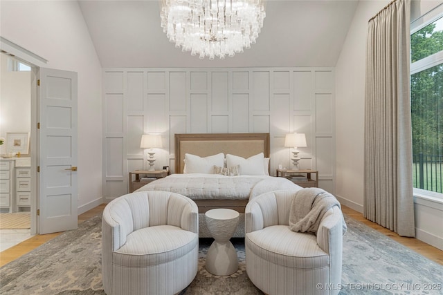 bedroom featuring vaulted ceiling, light wood finished floors, and a notable chandelier