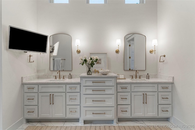 full bathroom with double vanity, baseboards, and a sink