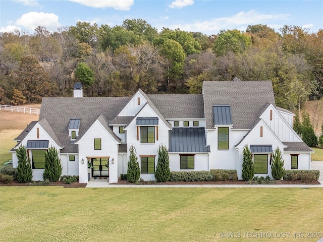 modern inspired farmhouse with metal roof, a shingled roof, a front lawn, a standing seam roof, and a chimney