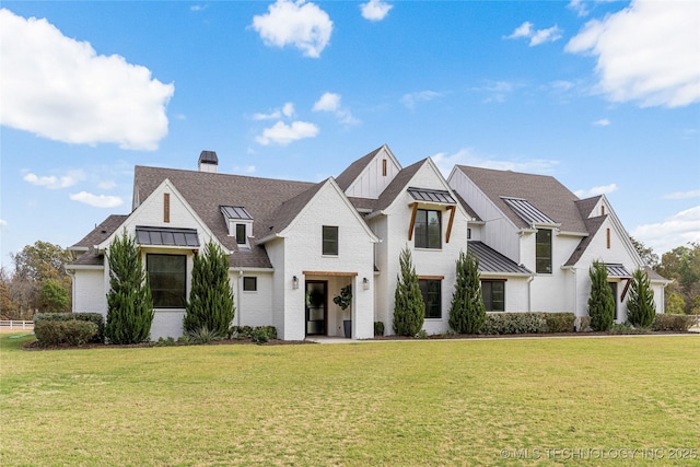 view of front of home with a standing seam roof, brick siding, metal roof, and a front yard