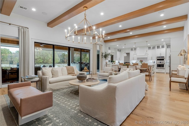 living room with a wealth of natural light, beam ceiling, visible vents, and light wood finished floors