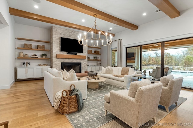 living room with baseboards, visible vents, a stone fireplace, light wood-type flooring, and beam ceiling