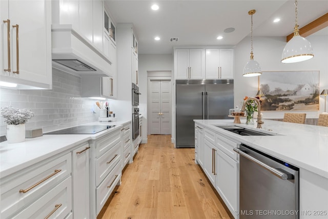 kitchen featuring white cabinets, custom exhaust hood, stainless steel appliances, light countertops, and a sink