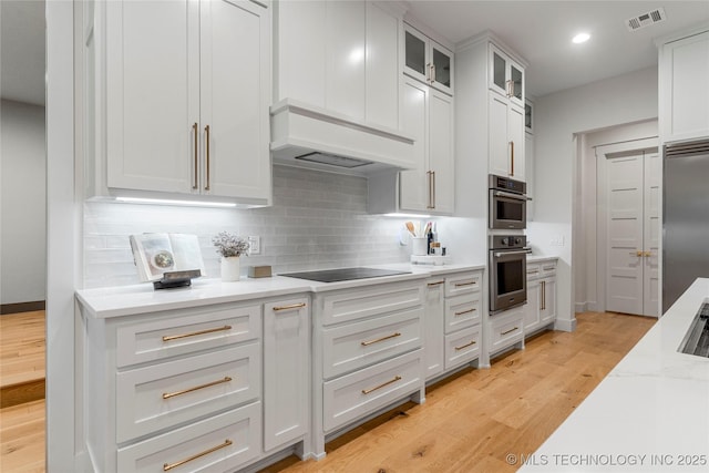 kitchen featuring stainless steel appliances, tasteful backsplash, visible vents, custom range hood, and light wood-type flooring