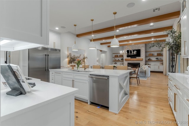 kitchen with stainless steel appliances, a sink, beam ceiling, a center island, and light wood finished floors