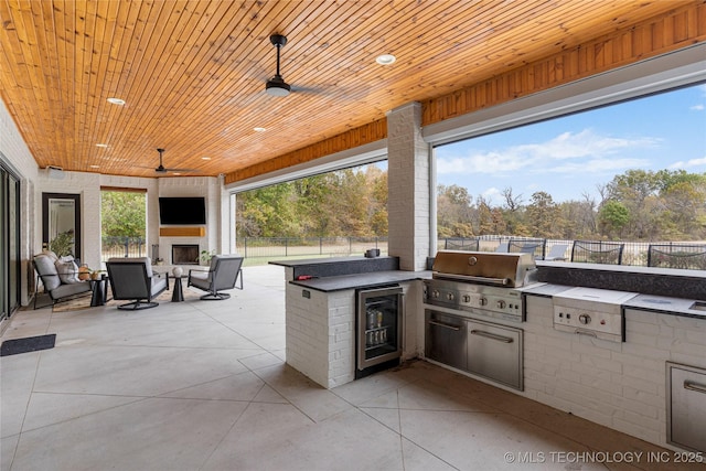 view of patio with a fireplace, grilling area, area for grilling, beverage cooler, and a fenced backyard