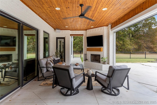 view of patio / terrace with ceiling fan, an outdoor living space with a fireplace, and fence