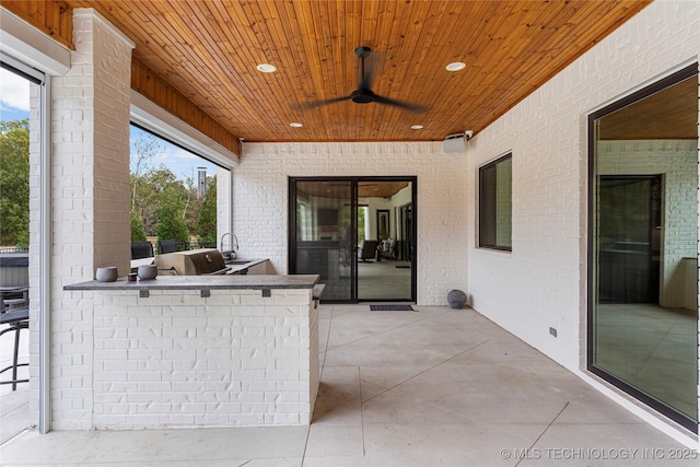 view of patio / terrace with a ceiling fan, outdoor wet bar, a sink, and area for grilling