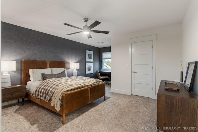 carpeted bedroom featuring visible vents, an accent wall, a ceiling fan, baseboards, and wallpapered walls