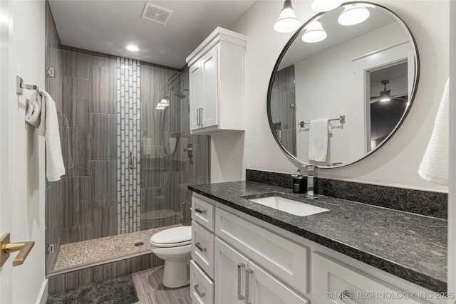 full bathroom with toilet, a stall shower, vanity, and visible vents