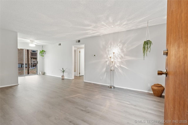 unfurnished living room featuring a textured ceiling, visible vents, a ceiling fan, and wood finished floors