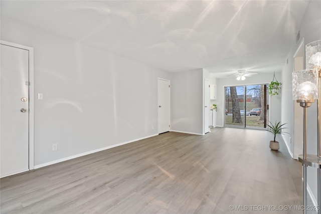 empty room with a textured ceiling, baseboards, ceiling fan, and wood finished floors