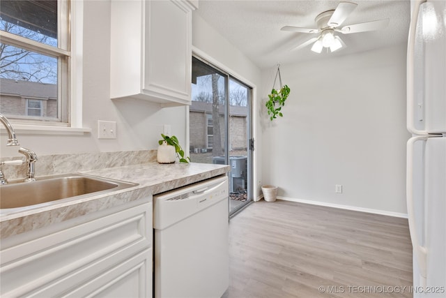 kitchen featuring light countertops, white appliances, white cabinetry, a sink, and light wood-style floors