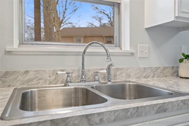 details with light countertops, a sink, and white cabinets
