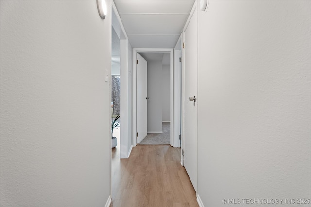 hallway with baseboards and light wood-style floors
