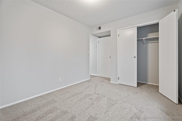 unfurnished bedroom with a closet, a textured ceiling, visible vents, baseboards, and carpet floors