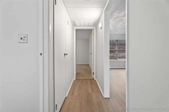 hall with baseboards, visible vents, and light wood-type flooring